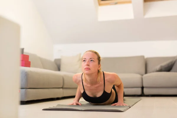 Piękna blondynka ćwicząca w domu. Kobieta ćwiczy jogę w domu. Fit girl za pomocą samouczków treningu dla zdrowego aktywnego stylu życia. Kobieta stosująca kwarantannę do treningu w domu. — Zdjęcie stockowe