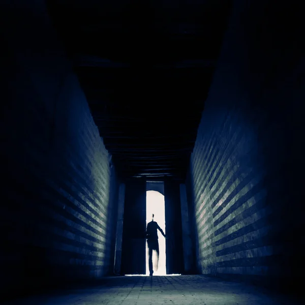 Entrando en lo desconocido. Las personas silueta que entra a través de la puerta de entrada a la sala de contraluz oscuro. Entrando en lo desconocido. — Foto de Stock