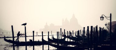 Romantik İtalyan şehri Venedik, bir Dünya Mirası Alanı: geleneksel Venedik ahşap tekneleri, gondolcu ve Roma Katolik kilisesi Bazilikası di Santa Maria della Salute sisli arka planda