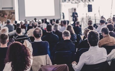 Sözcü İş Toplantısı 'nda konuşma yapacak. Konferans salonunda dinleyiciler. İş ve Girişimcilik. Arkadan tanınmayan insanlara odaklan.