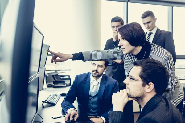 Business team che guarda i dati su più schermi di computer in ufficio aziendale. Una donna d'affari che punta sullo schermo. Uomini d'affari che fanno trading online. Business, imprenditorialità e concetto di lavoro di squadra — Foto Stock