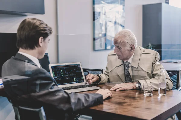 Asesor financiero consultando a cliente senior con su estrategia de inversión. — Foto de Stock