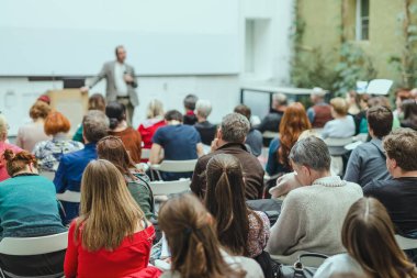 Üniversitedeki konferans salonunda sunum yapan adam.
