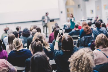 Üniversitedeki konferans salonunda sunum yapan adam.
