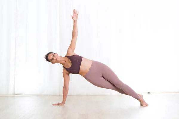 Retrato de una joven deportista activa practicando yoga en estudio. Estilo de vida activo saludable, ejercicio en interiores en el gimnasio —  Fotos de Stock