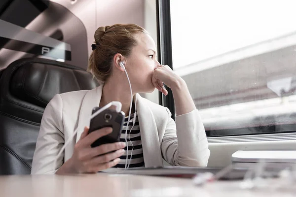 Geschäftsfrau kommuniziert auf Bahnreise per Handy. — Stockfoto