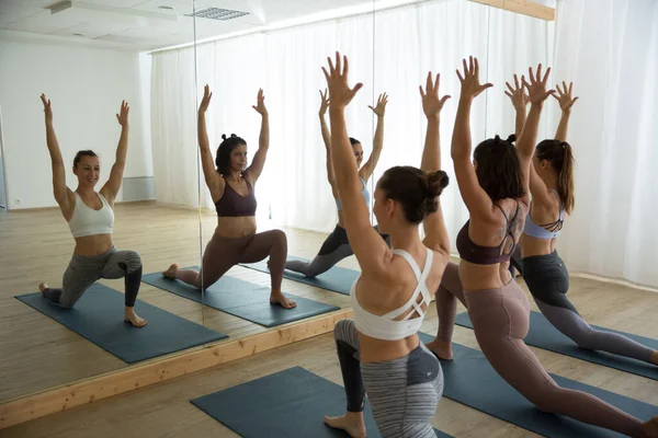 Grupa młodych, wysportowanych kobiet w studio jogi, ćwiczących jogę przed lustrem. Zdrowy aktywny tryb życia, ćwiczenie wewnątrz sali gimnastycznej — Zdjęcie stockowe