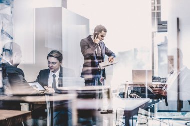 İş adamı şirket ofisinde cep telefonuyla konuşuyor..