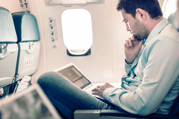 Üzletember dolgozik laptop a repülőn. — Stock Fotó