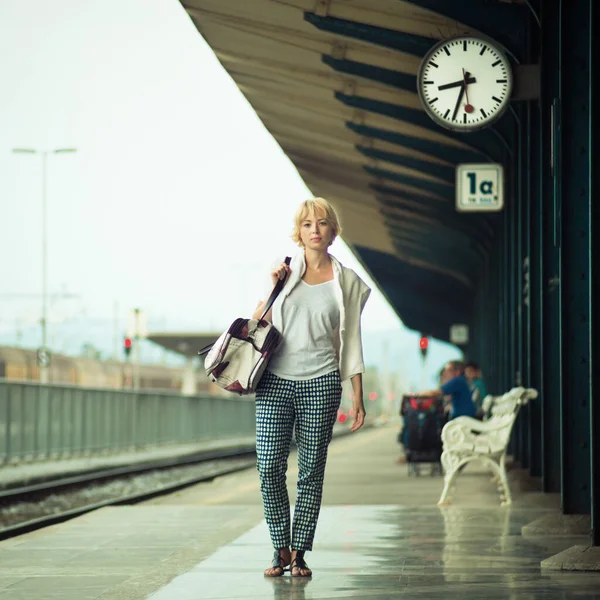 Блондинка-кавказка ждет на вокзале с сумкой — стоковое фото