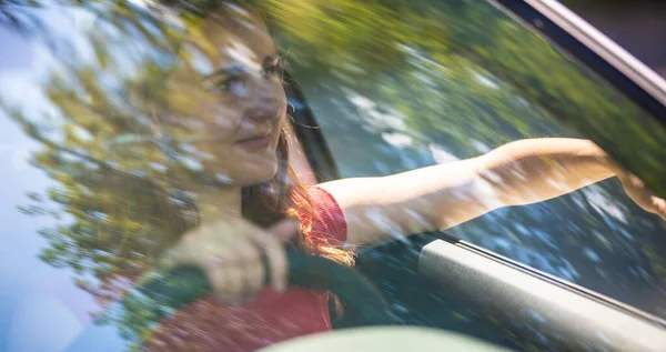 Bewegung blaues Bild der glücklichen jungen Frau am Steuer eines Autos auf einem Sommer-Roadtrip in den Urlaub. Schuss durch Windschutzscheibe. — Stockfoto