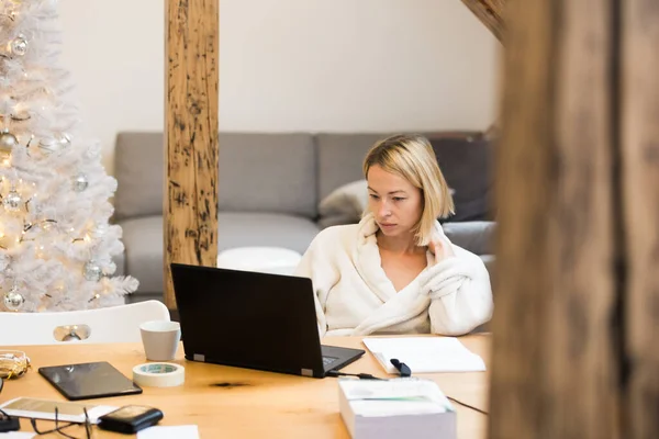 Joven empresaria vestida con albornoz cálido y acogedor que trabaja remotamente desde casa en invierno en época de Navidad durante la pandemia del virus corona 2020. Trabajo desde casa, selector en su lugar, concepto. — Foto de Stock