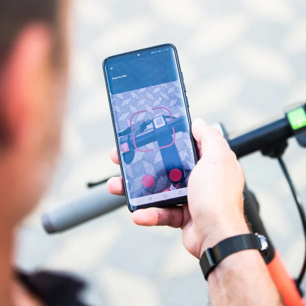 Närbild av hand och smartphone, låsa upp docklös elektrisk skoter för uthyrning med debranded generiska telefon app. — Stockfoto