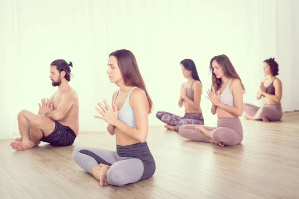Grupo de jovens esportivas mulheres atraentes no estúdio de ioga, praticando aula de ioga com instrutor, alongamento e relaxamento durante o treino. Estilo de vida ativo saudável, exercitando-se no ginásio. — Fotografia de Stock