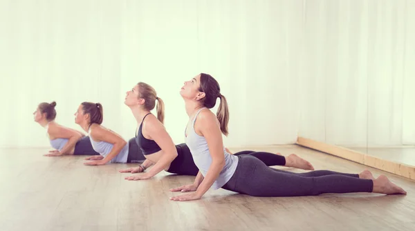Група молодих спортивних сексуальних жінок в студії йоги, практикує урок йоги з інструктором, формуючи лінію в позі асани. Здоровий активний спосіб життя, що працює в приміщенні в спортзалі — стокове фото