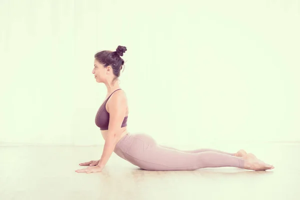 Portret van een prachtige actieve sportieve jonge vrouw die yoga beoefent in de studio. Mooi meisje praktijk Sasangasana, konijn yoga pose. Gezonde actieve levensstijl, sporten in de fitnessruimte — Stockfoto