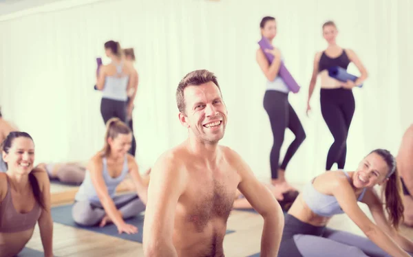 Portret wesołego mężczyzny instruktora jogi gorącej relaks po udzieleniu lekcji jogi dużej grupie atrakcyjnych sportowców. Zdrowy aktywny tryb życia, ćwiczenie wewnątrz sali gimnastycznej. — Zdjęcie stockowe