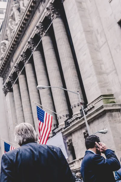 Empresario hablando por teléfono en Wall Street en Nueva York con banderas estadounidenses y bolsa de Nueva York en segundo plano. —  Fotos de Stock