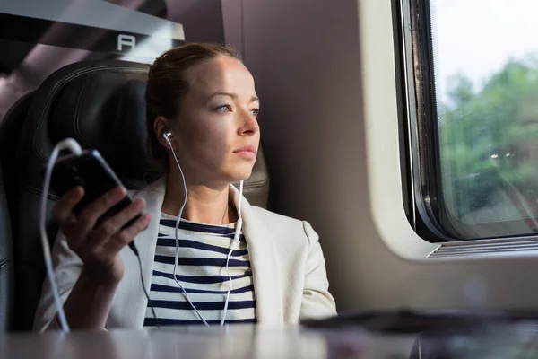 Geschäftsfrau kommuniziert auf Bahnreise per Handy. — Stockfoto