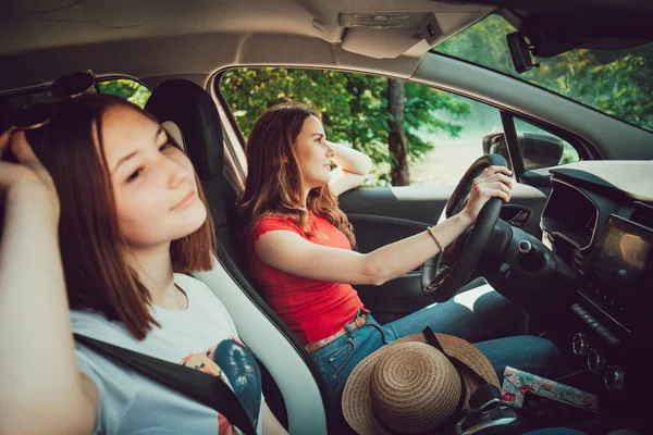 Twee jonge vrouwelijke vrienden rijden in de auto, genieten van road trip in de zomer. — Stockfoto