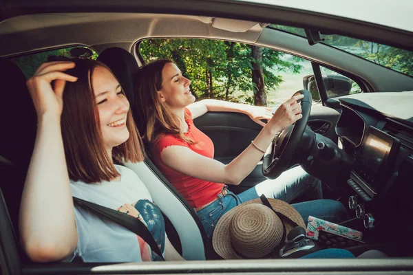 Två unga kvinnliga vänner kör, lyssnar på bra musik i bilen, njuta av road trip på sommaren. — Stockfoto