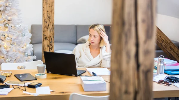 Jonge vrouwelijke ondernemer met warme badjas die 's winters in de winter op afstand werkt Kerst in 2020 corona virus pandemie. Werk van thuis, selter op zijn plaats, concept. — Stockfoto