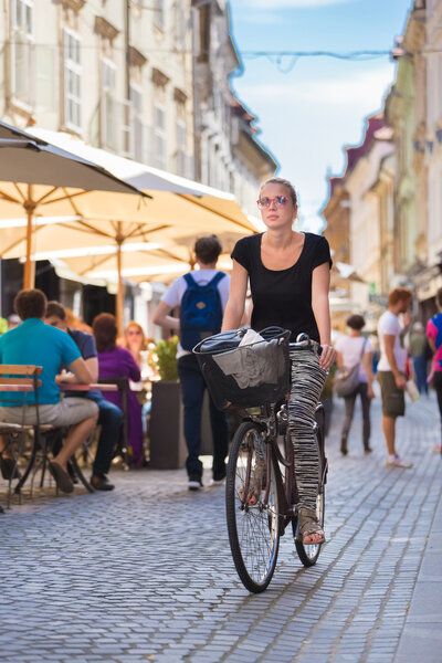 Woman riding bicycle in city center.