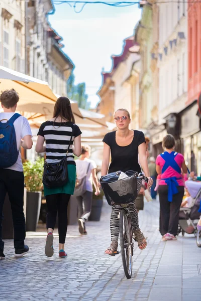 女人骑自行车在城市的中心. — 图库照片