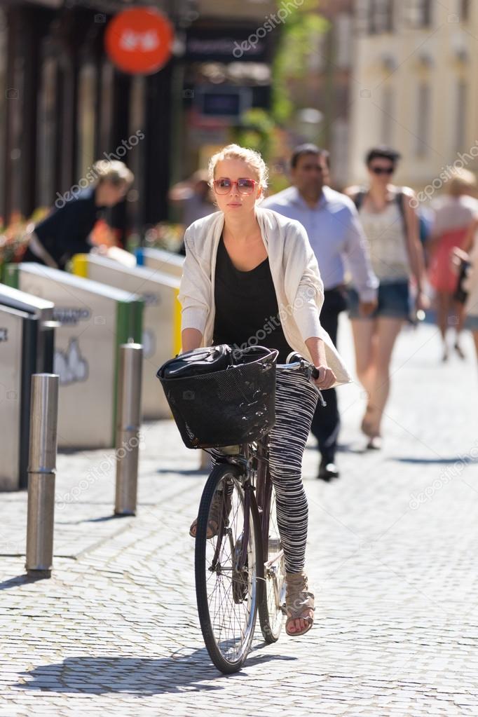 Woman riding bicycle in city center.