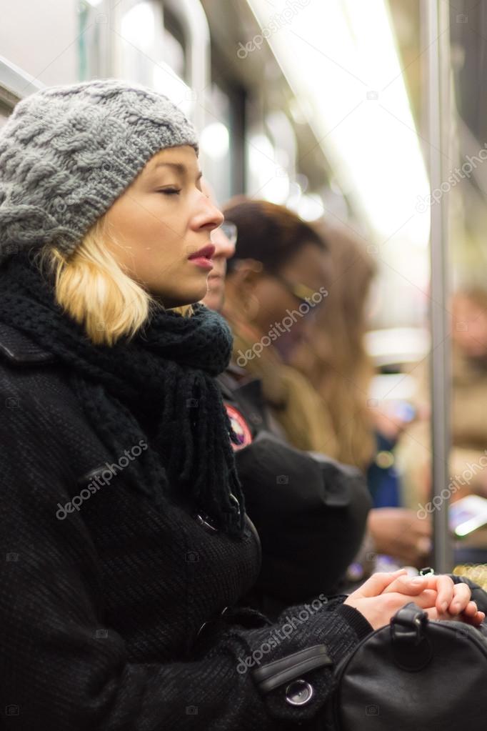 Woman napping on subway full of people.