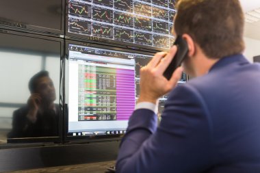 Stock trader looking at computer screens. clipart