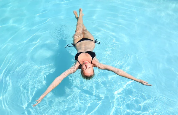 Beautiful Caucasian lady floating in swimming pool. — Stock Photo, Image