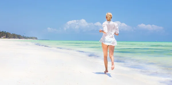Vrouw draait op het strand in wit overhemd. — Stockfoto