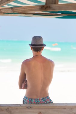 Hipster adam tropikal kum plajındaki şapkalı.