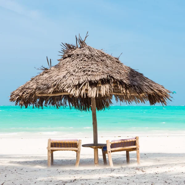 Dwa leżaki i parasol na tropikalnej plaży. — Zdjęcie stockowe