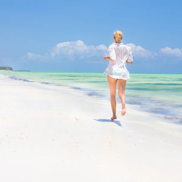Mujer corriendo en la playa en camisa blanca . — Foto de Stock