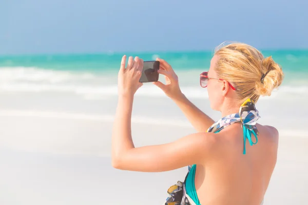 ビーチで写真を撮る女性は. — ストック写真