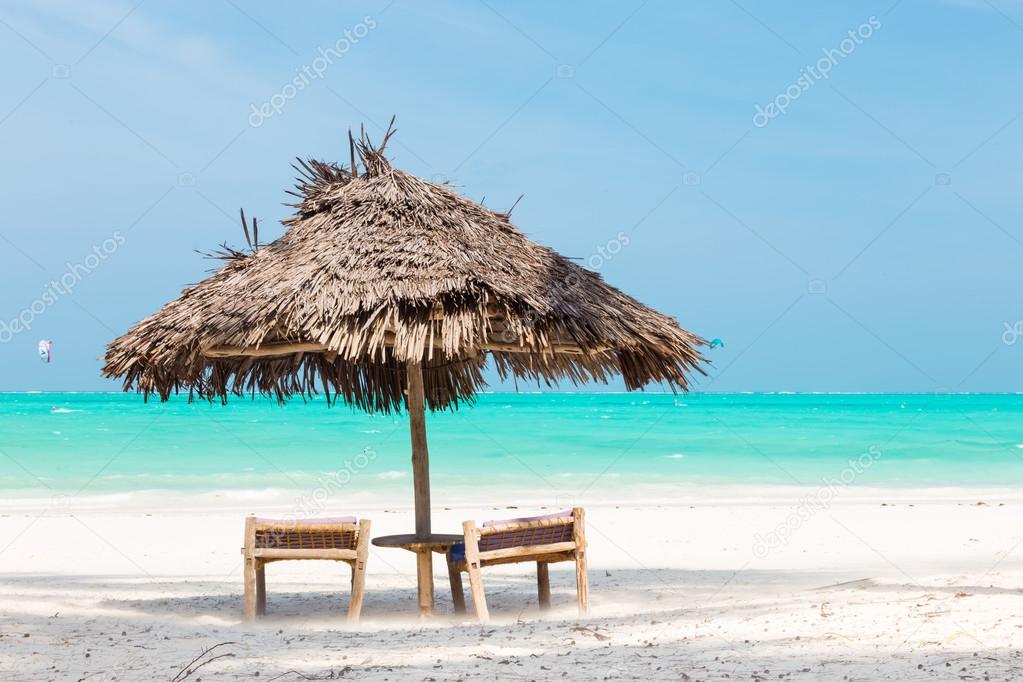 Two deck chairs and umbrella on tropical beach.