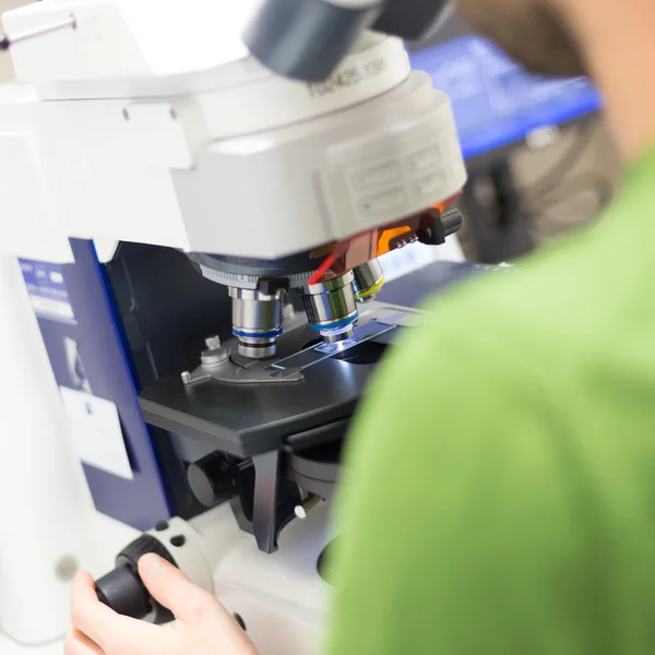 Scientist microscoping on fluorescent microscope. — Stock Photo, Image