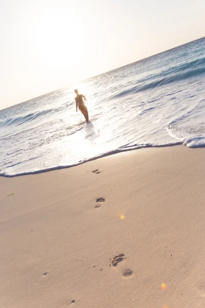 Mulher correndo na praia ao pôr do sol . — Fotografia de Stock