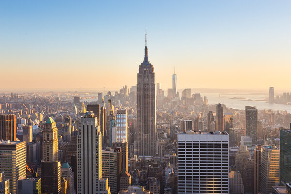 New York City. Manhattan downtown skyline with illuminated Empire State Building and skyscrapers at sunset seen from Top of the Rock observation deck. Vertical composition.