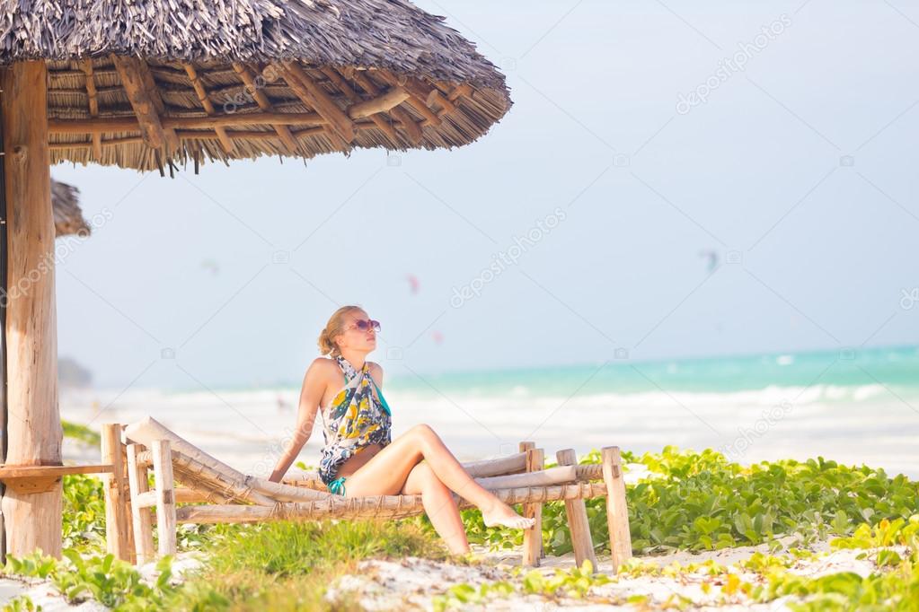 Woman sunbathing on tropical beach.