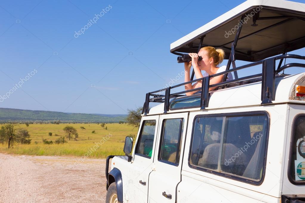 Woman on safari looking through binoculars.