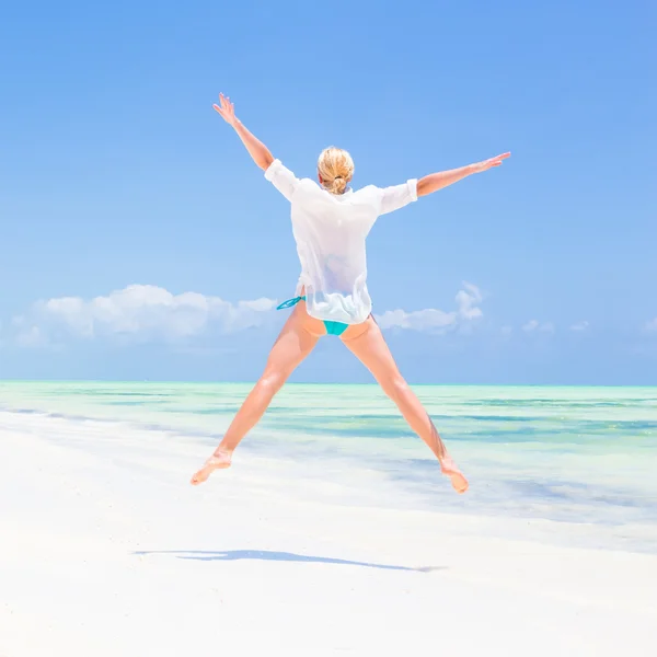 Schönes Mädchen springt am tropischen Strand. — Stockfoto