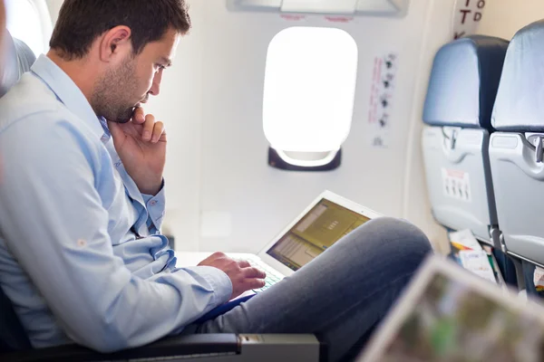 Geschäftsmann arbeitet mit Laptop im Flugzeug. — Stockfoto