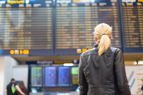Female traveller checking flight departures board. — Stock Photo, Image