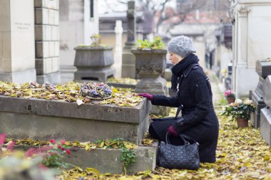 Solitary woman visiting relatives grave. clipart
