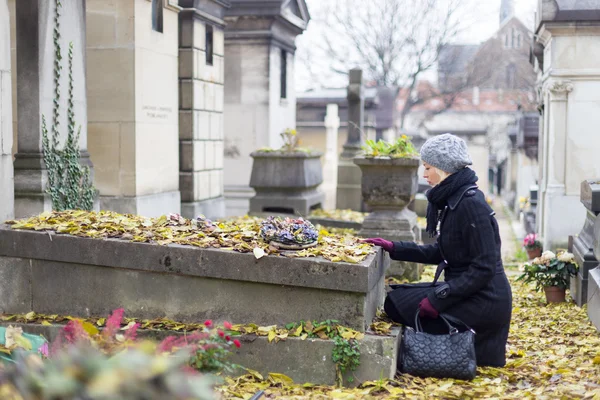 Mujer solitaria visitando tumba parientes . — Foto de Stock