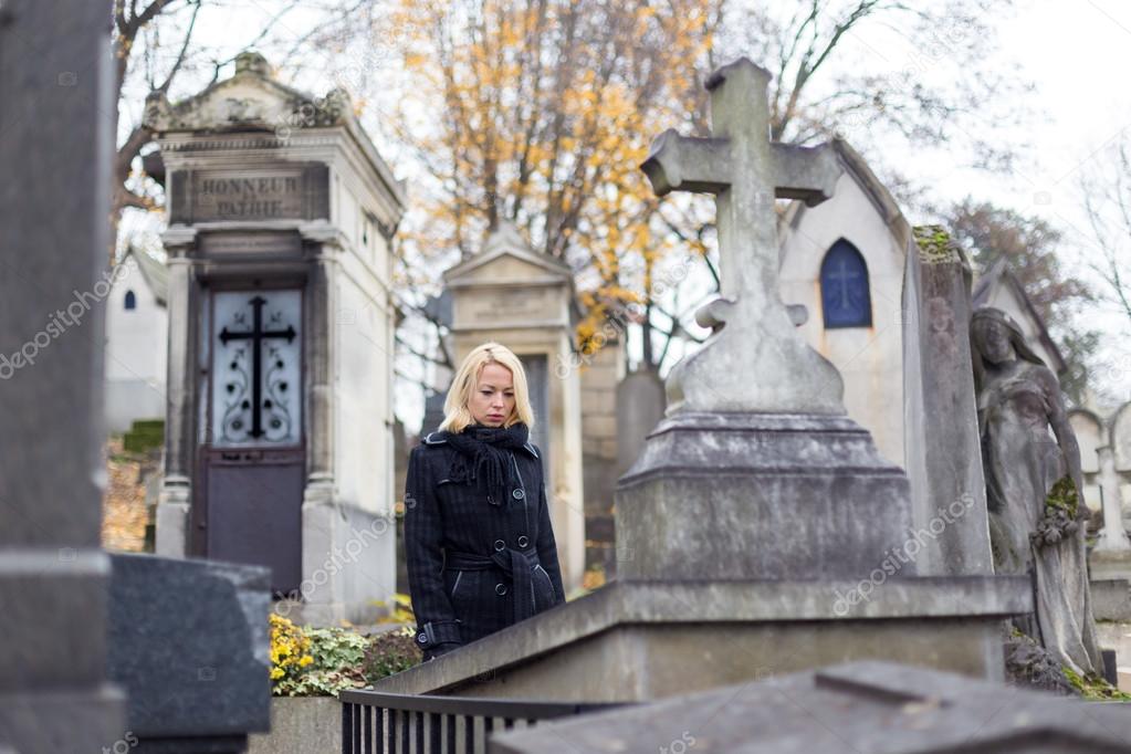 Solitary woman visiting relatives grave.