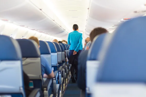 Interior of airplane with stewardess walking the aisle. — Stock Photo, Image